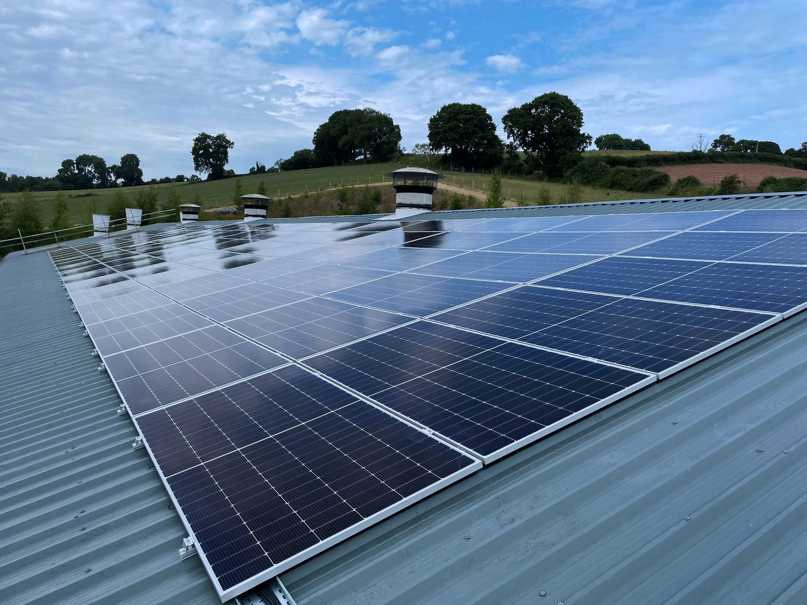 Bifacial solar panels on a farm roof installed by Novalux, fields behind