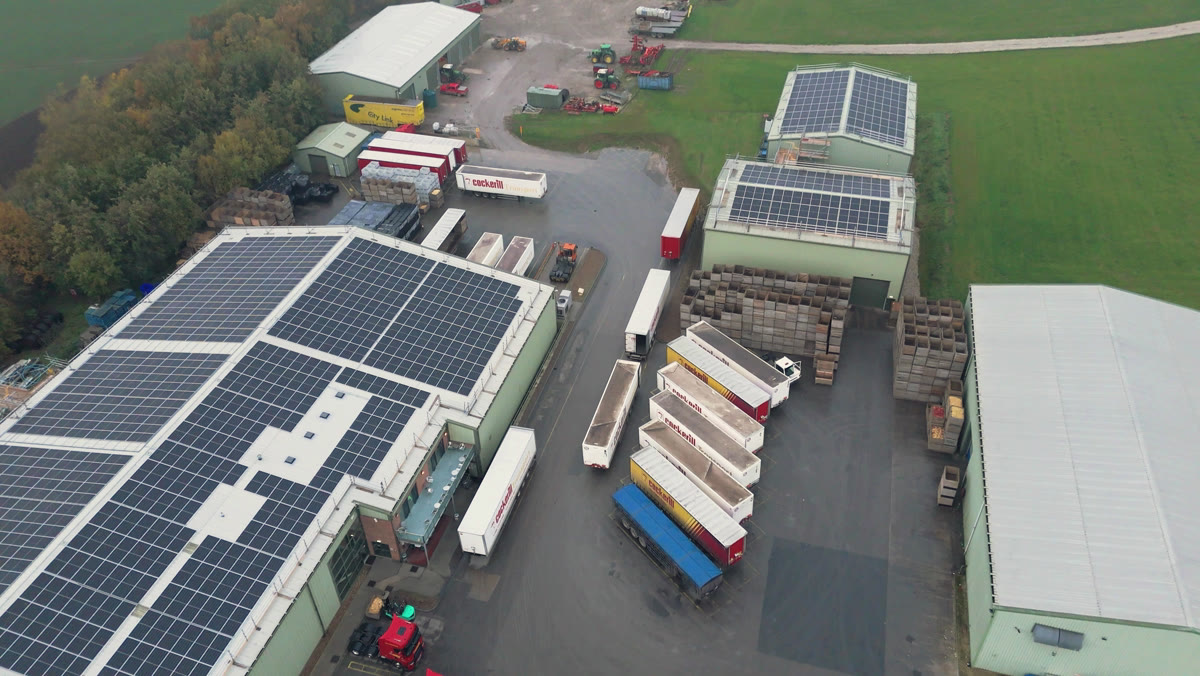 Birds-eye drone view over the R.S. Cockerill farm buildings with Novalux rooftop solar across three roofs